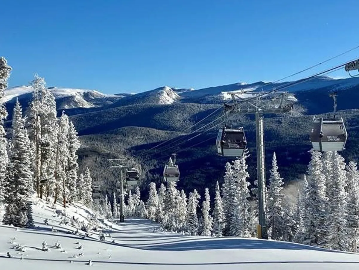 A picturesque winter scene featuring ski lifts rising above snow-covered mountains and tall pine trees. The expansive view captures both the excitement of skiing and the serene beauty of the winter landscape, inviting guests to imagine themselves enjoying the slopes and snowy adventures nearby.